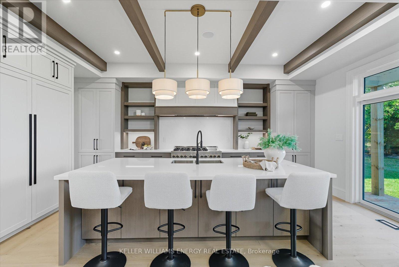 A modern kitchen with white chairs and a central island.