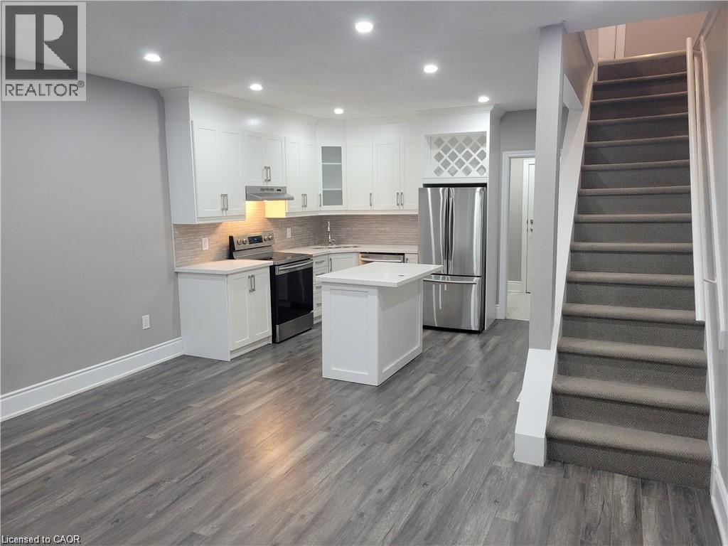 A well-lit kitchen with a refrigerator, stove, and cabinets.