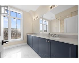 A bathroom with a large mirror and a window with a view of trees.