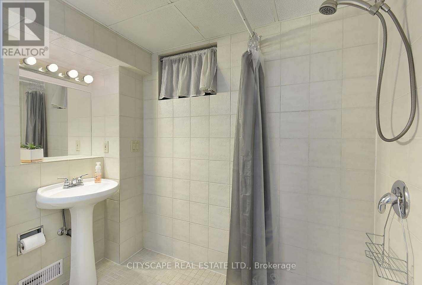 A white sink in a bathroom with a shower head and curtains.