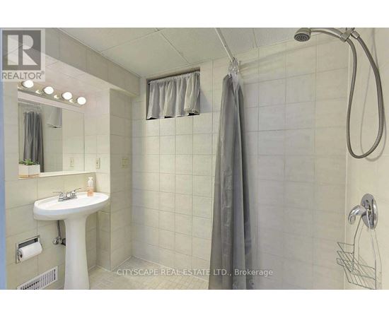 A white sink in a bathroom with a shower head and curtains.