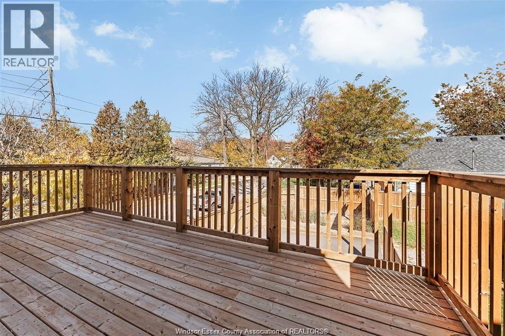 A wooden deck with a railing and trees in the background.