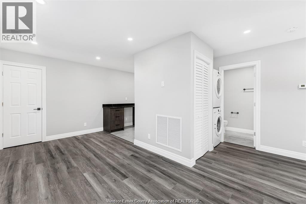 A spacious room with wood flooring and white walls.