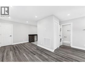 A spacious room with wood flooring and white walls.