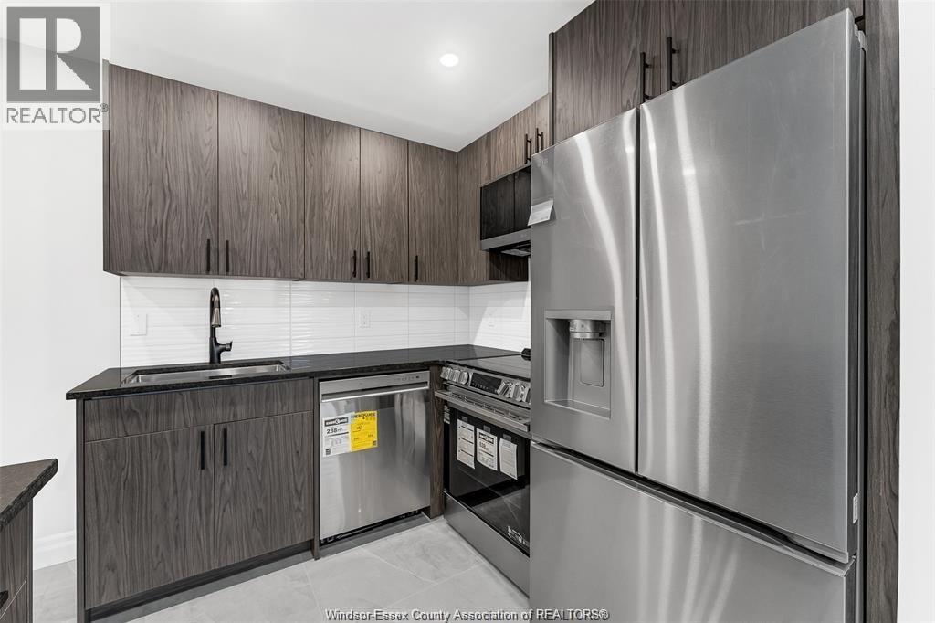 A kitchen with a stainless steel refrigerator and wooden cabinets.