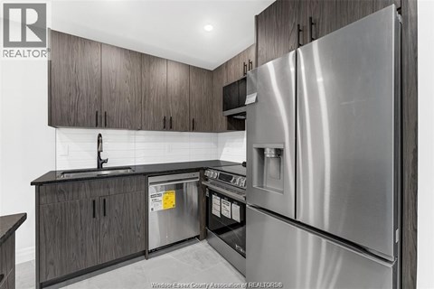 A kitchen with a stainless steel refrigerator and wooden cabinets.