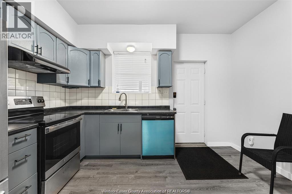 A kitchen with a black chair and a black mat on the floor.