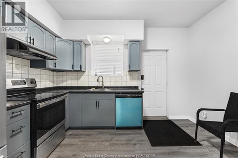 A kitchen with a black chair and a black mat on the floor.