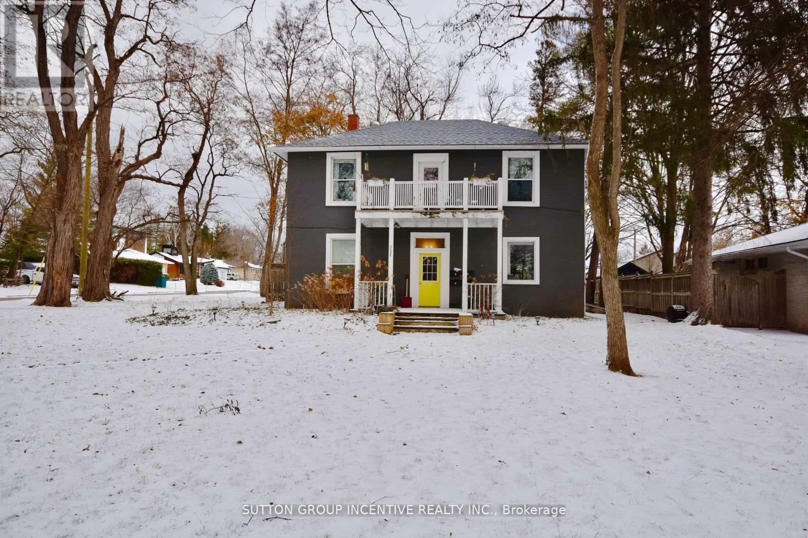 A grey house with a yellow door in a snowy landscape.