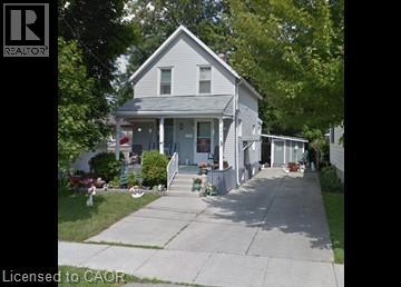 A white house with a porch and a tree in front.
