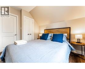 A bedroom with a bed, two pillows, a nightstand with a lamp, and a wall-mounted light fixture.