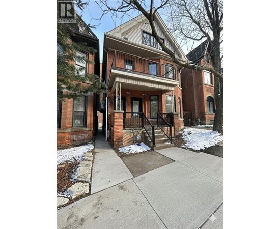 A house with a brown brick facade and a white porch.
