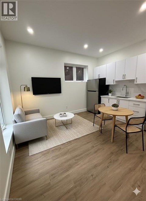 A living room with a grey couch, a white chair, a wooden table, and a television mounted on the wall.