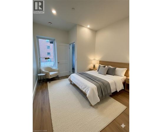 A bedroom with a large bed and a chair by the window.