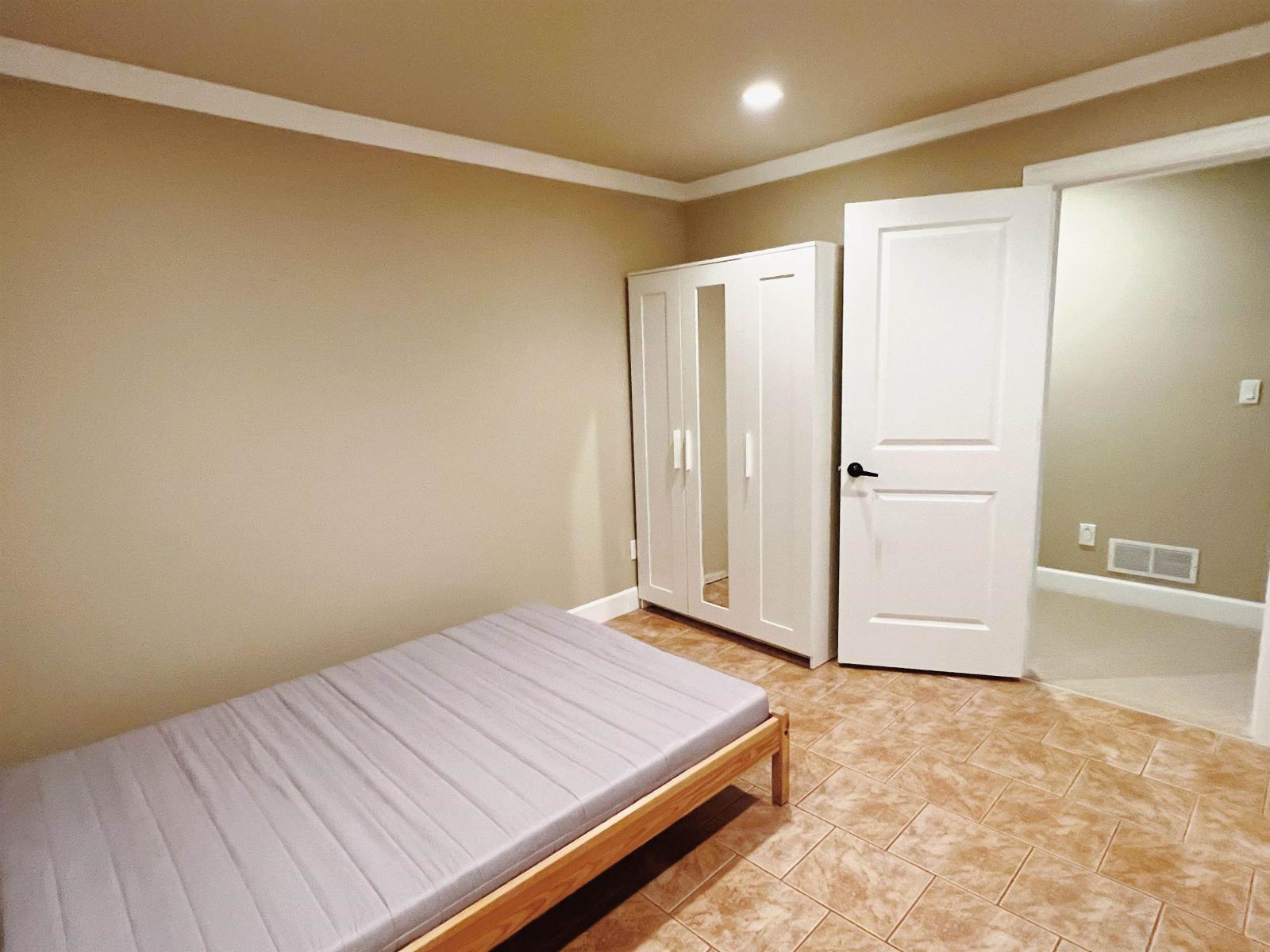 A bedroom with a bed, wardrobe, and cupboard.