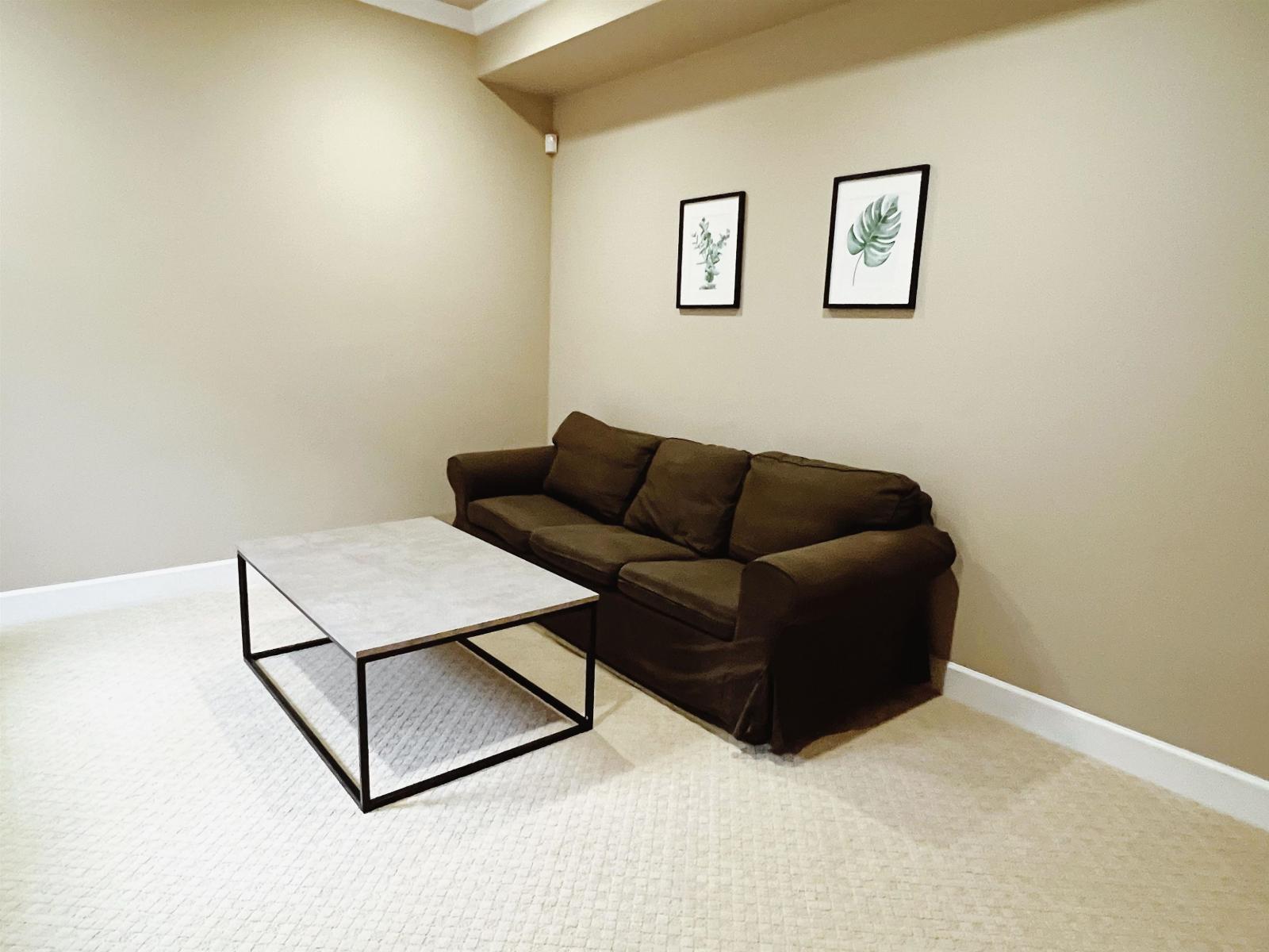 A brown couch sits in a room with a coffee table in front of it.