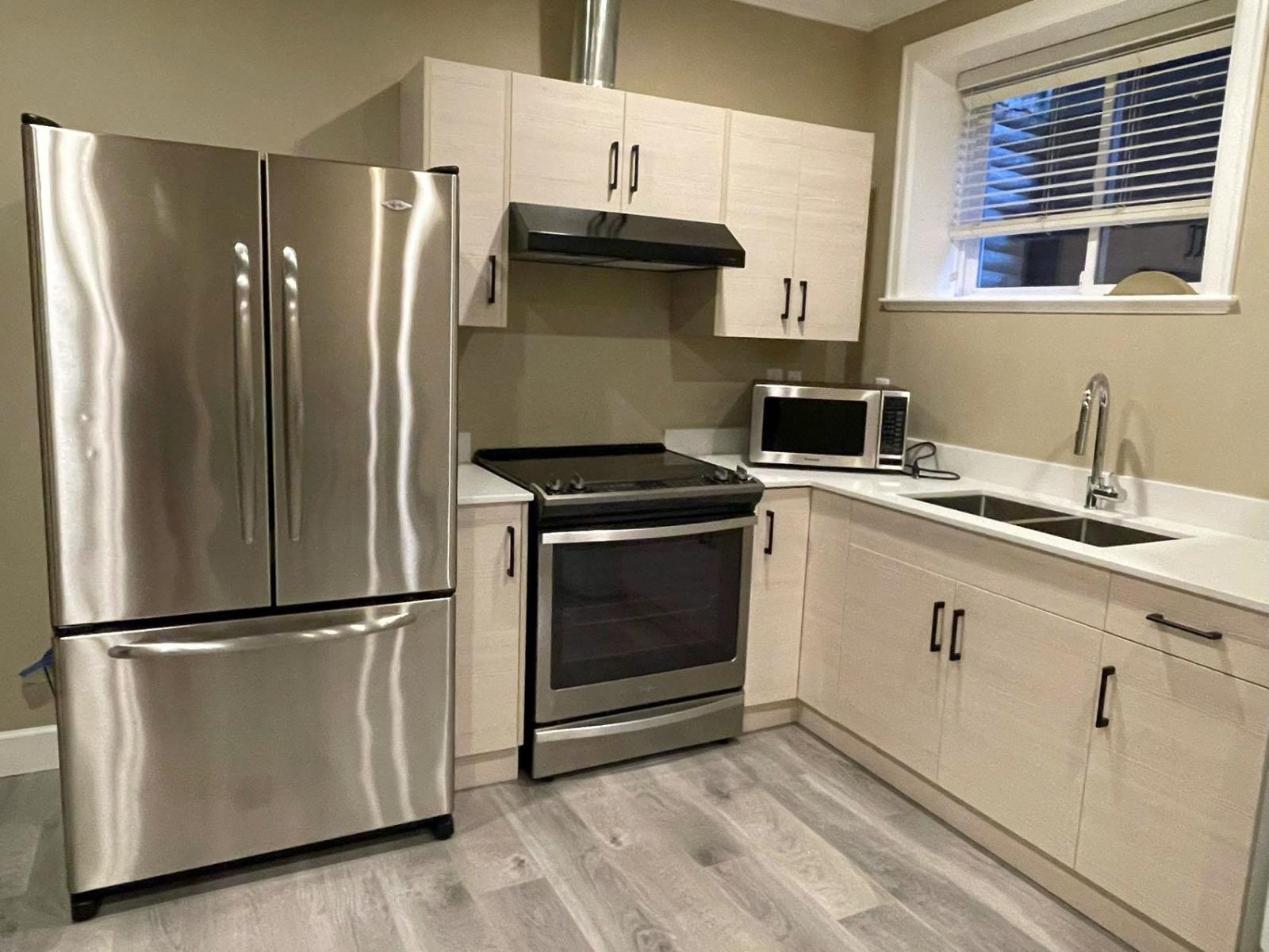A kitchen with a stainless steel refrigerator, oven, and microwave.