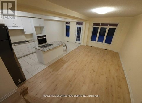 A kitchen with white cabinets and a wooden floor.