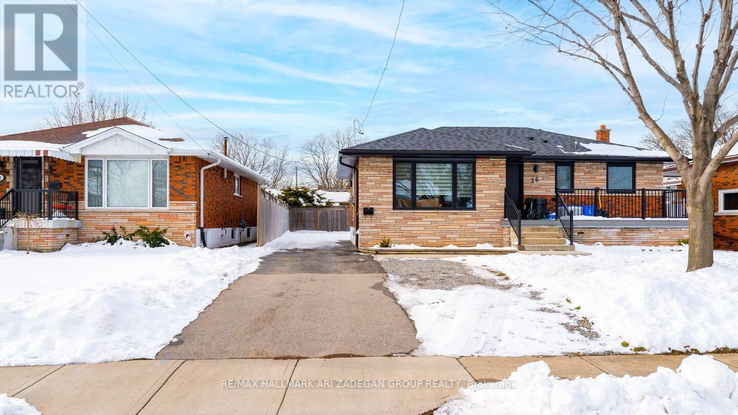 A house with a snow-covered front yard and a dog standing in the driveway.