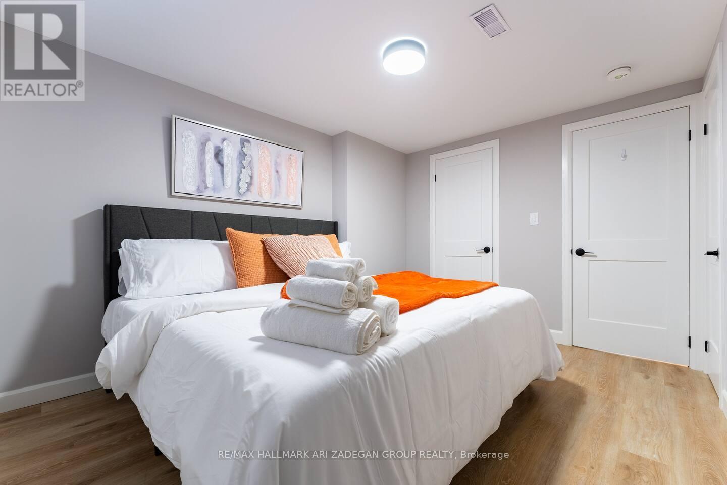 A bedroom with a large bed and a painting above it.