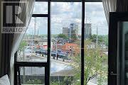 A view from a balcony overlooking a cityscape with buildings, roads, and construction cranes.
