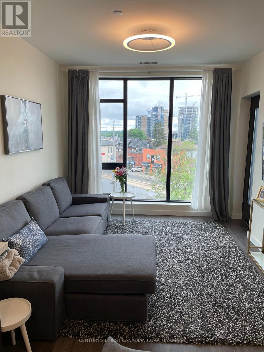 A living room with a grey sofa and a large window overlooking the city.