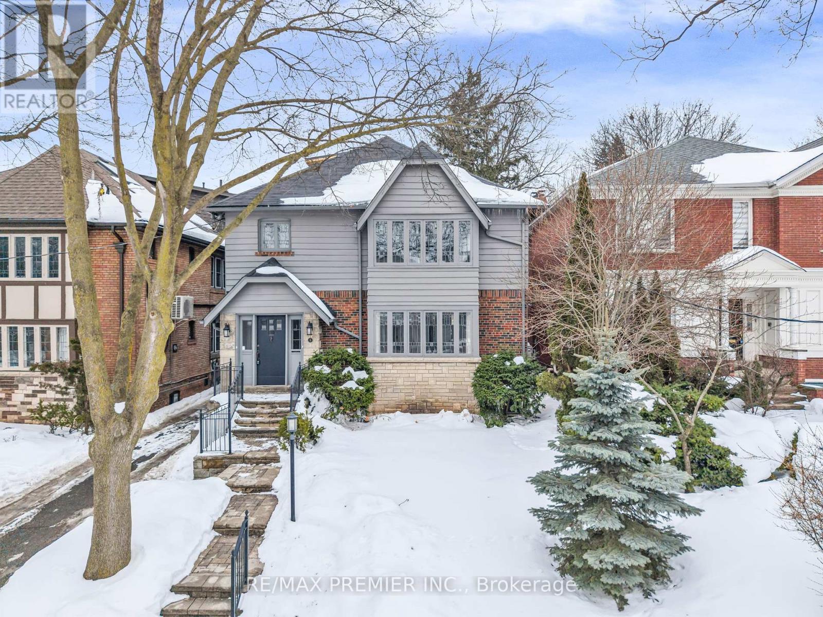 A house with a grey roof and a black door is surrounded by snow.