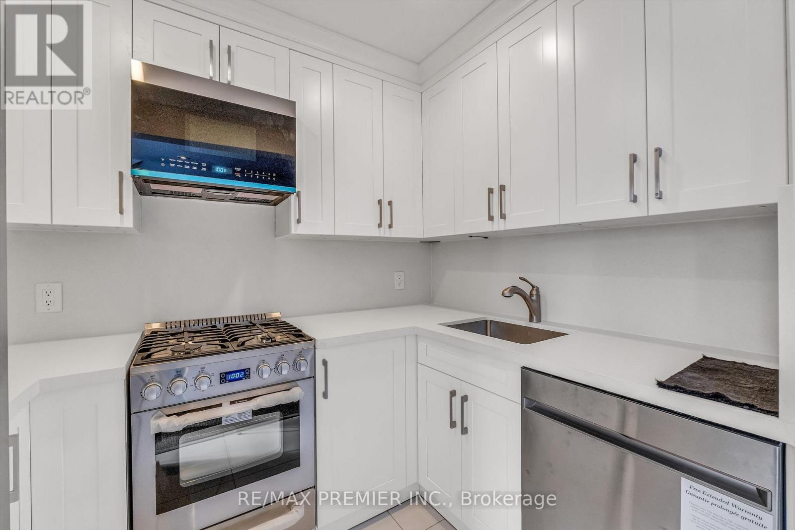 A white kitchen with a stove top oven and a dishwasher.