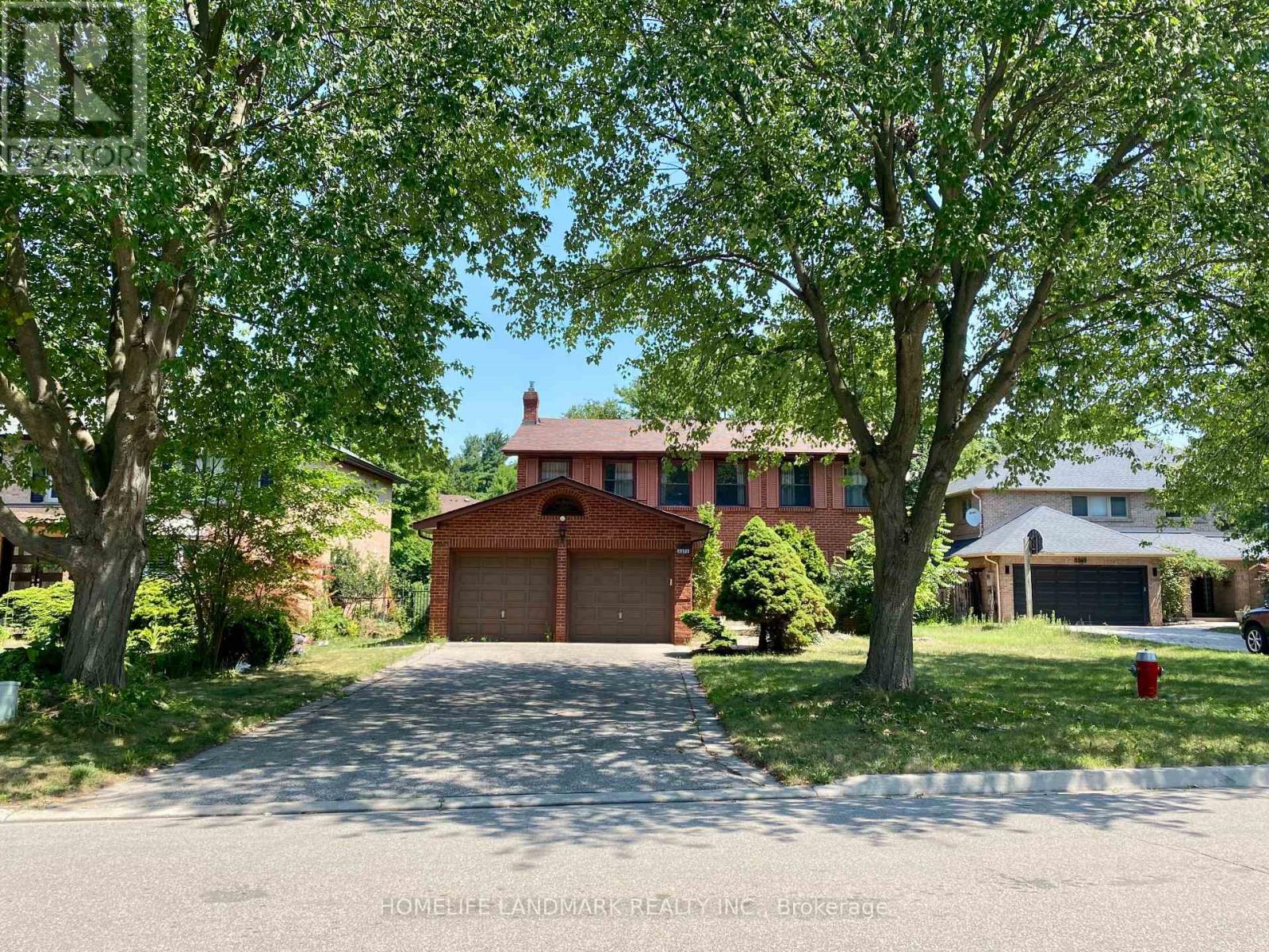 A red brick house with a driveway in front.