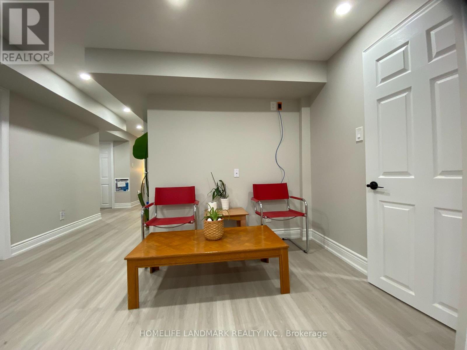 A room with a wooden table and two red chairs.