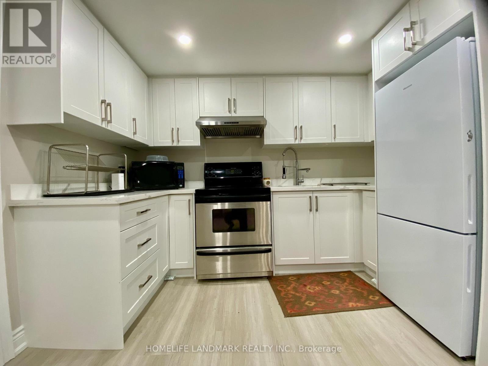 A kitchen with white cabinets and a refrigerator.