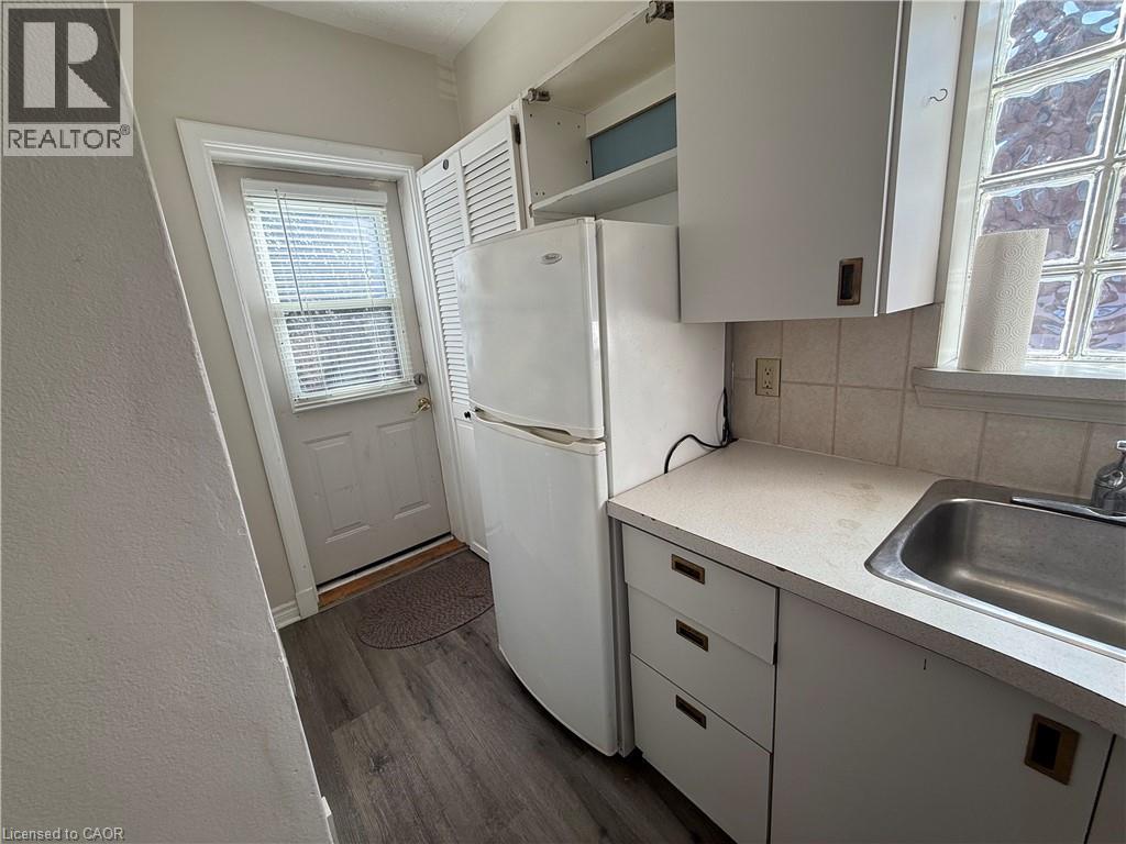 A small kitchen with a white refrigerator, white cabinets, and a white sink.