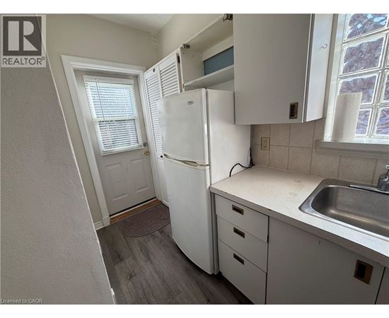 A small kitchen with a white refrigerator, white cabinets, and a white sink.