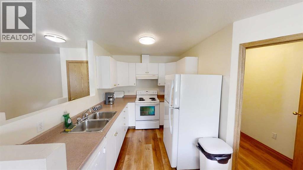 A white kitchen with a sink, stove, and refrigerator.