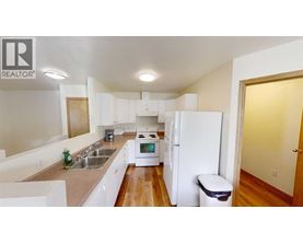 A white kitchen with a sink, stove, and refrigerator.