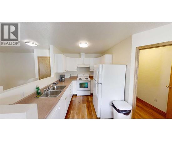 A white kitchen with a sink, stove, and refrigerator.