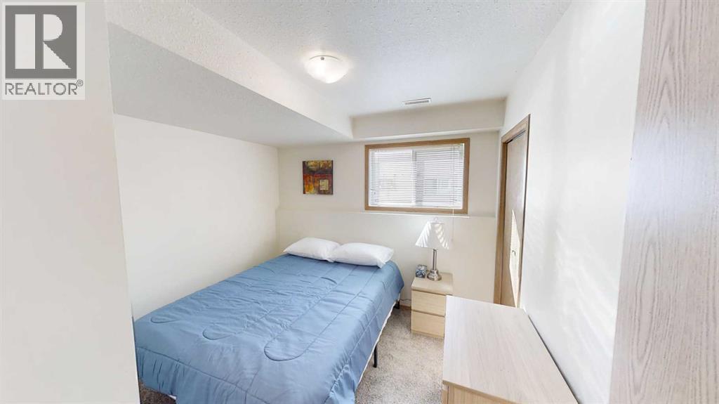A bedroom with a blue bedspread and a window with blinds.