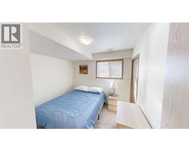 A bedroom with a blue bedspread and a window with blinds.