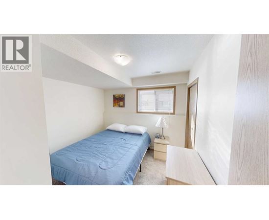 A bedroom with a blue bedspread and a window with blinds.