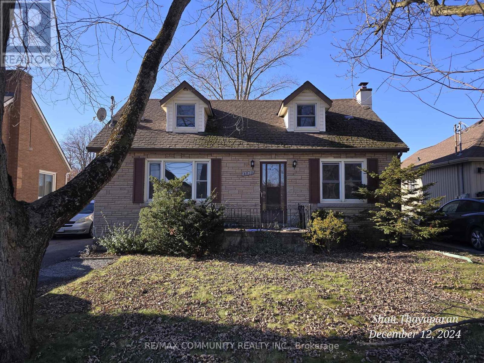 A house with a red roof and a tree in front of it.