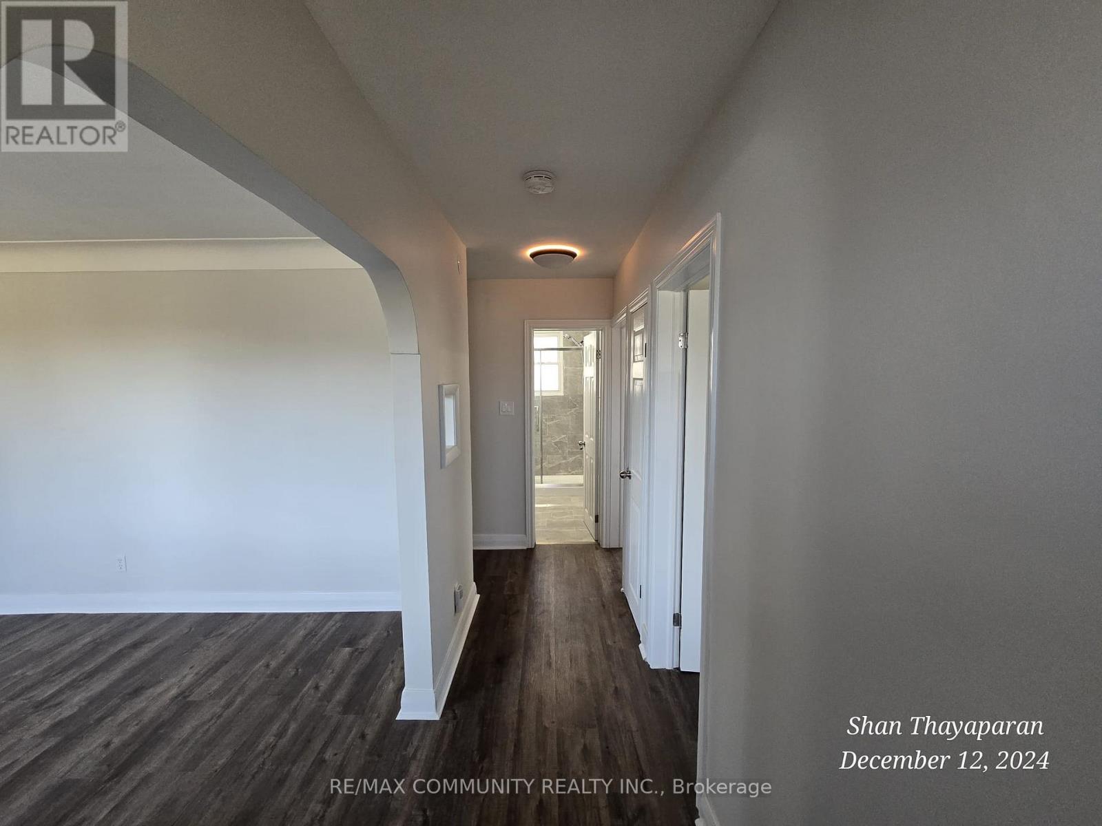 A hallway with wood flooring and white walls.