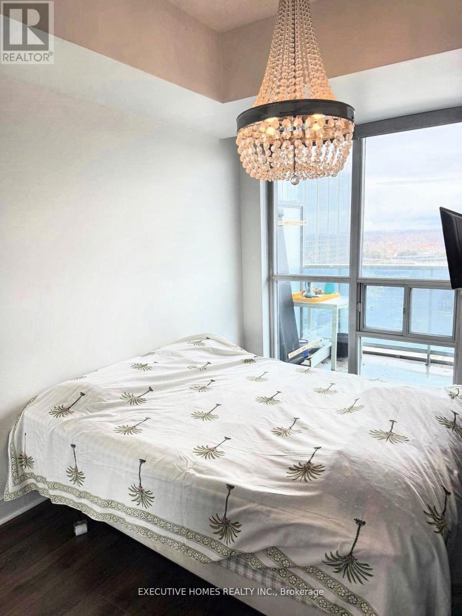 Bedroom with a bed covered in a white sheet with palm tree prints on it.