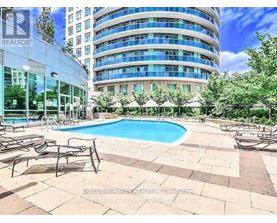 A swimming pool surrounded by lounge chairs in front of a multi-story building.