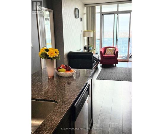 A kitchen with a red chair and a bowl of fruit on the counter.