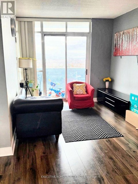A living room with a red chair and a black couch.