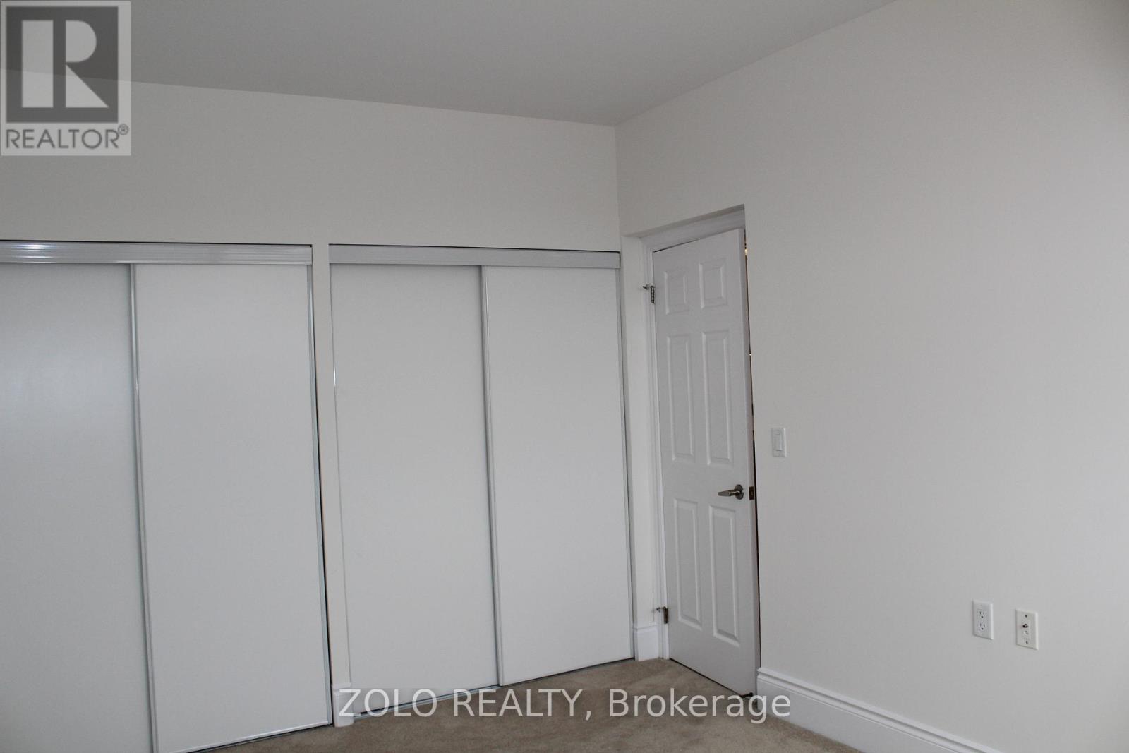 A white bedroom with a door and two closets.