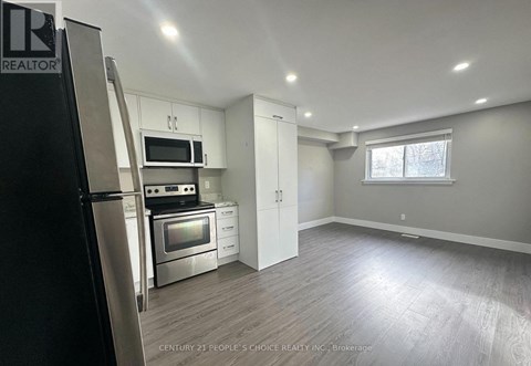 A kitchen with white cabinets and a black refrigerator.