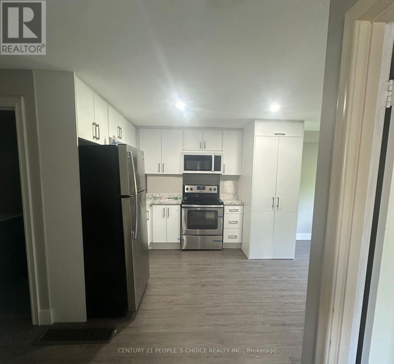 A kitchen with white cabinets and a black refrigerator.