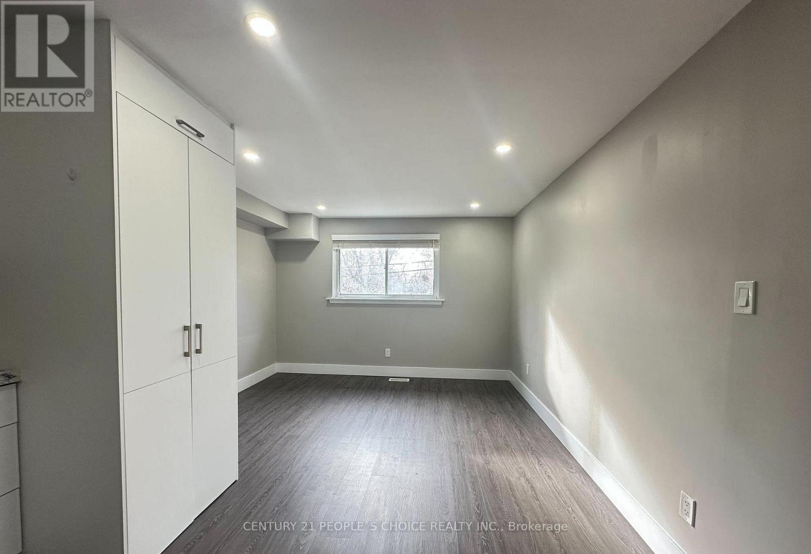 A spacious room with a window and wooden flooring.