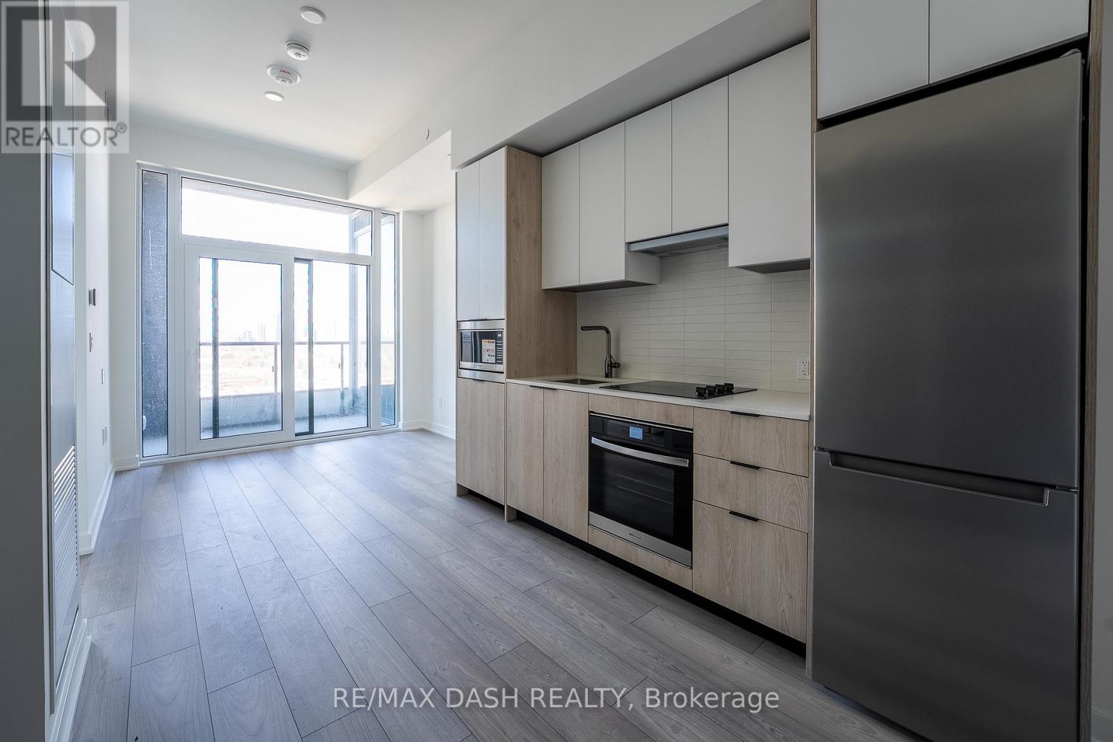 A modern kitchen with a refrigerator, oven, and cabinets.